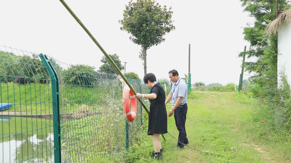 图为土桥村的网格员正在检查防溺水物资设置情况.jpg