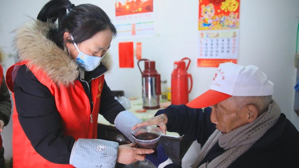图为社区志愿者上门送粥给行动不便的居民.jpg
