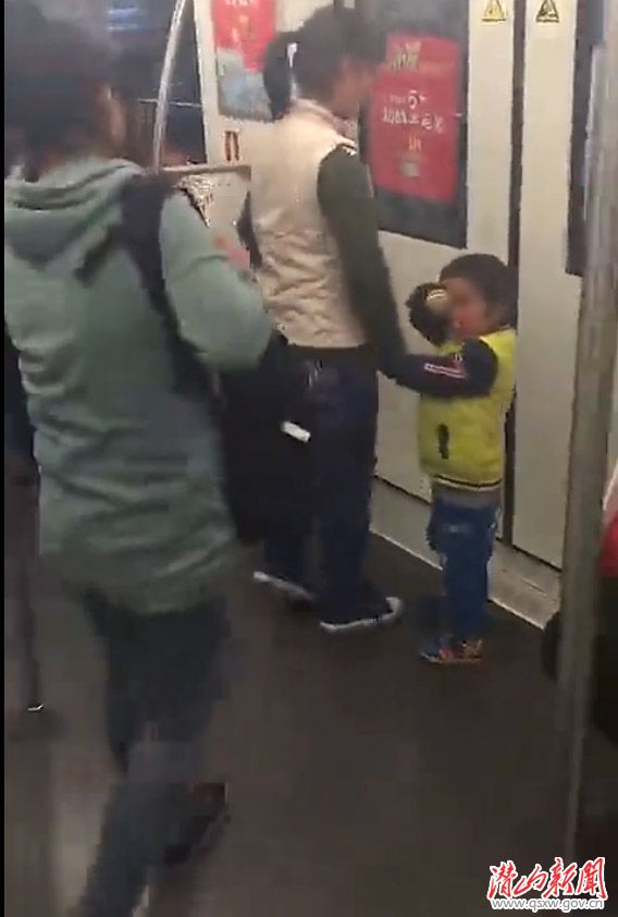 视频中，行乞女子带着小孩走到车门处。